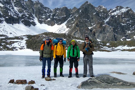 Four people stand at the base of a mountain with all of their gear.