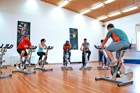 A cycling class in a studio with the instructor in the front of the class