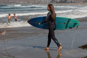 Female teen holding turquoise blue surf board with leash entering water with friends.  People, on Morro Strand State Beach, Morro Bay, CA.  A sunny warm, late summer day, with a number of visitors and families enjoying the sun, sand, and surf just north of Morro Rock.  07 October 2012.   Photo © 2012 Mike Michael L. Baird, mike {at] mikebaird d o t com, flickr.bairdphotos.com, Canon 5D Mark III, with Canon EF 100-400mm f4.5-5.6L IS USM Telephoto Zoom Lens, with circular polarizer, handheld, IS, RAW.  Aperture Priority, ISO 400. See EXIF for obtained shutter speed.  GPS encoding and compass direction was realtime from an on-camera Canon GP-E2 GPS Receiver.  To use this photo, see access, attribution, and commenting recommendations at http://www.flickr.com/people/mikebaird/#credit - Please add comments/notes/tags to add to or correct information, identification, etc.  Please, no comments or invites with badges, images, multiple invites, award levels, flashing icons, or award/post rules.   Critique invited.